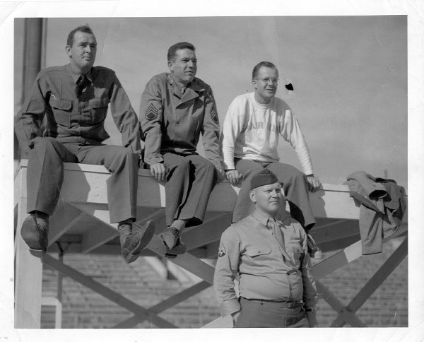 Four men seated on the wall, with Bill Hurley on the left.