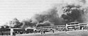 The first bombs to strike Hickam Field were dropped on Hawaiian Air Depot buildings and the hangar line, causing thick clouds of smoke to billow upward