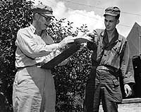 Photo # 80-G-440383:  Rear Admiral Arleigh A. Burke (left) reading dispatches at Munsan-Ni, Korea, August 1951