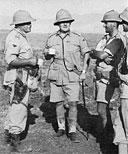 Enjoying a mug of tea after capturing Hobok are (l. to r.) Lieut.-Colonel W. Kirby, Commanding Officer of 3rd Transvaal Scottish (who was later killed in action at Sidi Rezeg), Brigadier B. F. Armstrong, and Major Harry Klein, Commanding Officer of No. 1 S.A. Armoured Car Company.