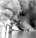 CAVITE NAVY YARD, Luzon, during a Japanese aerial attack. Early on the
morning of 8 December 1941 the Japanese struck the Philippine Islands. By the
end of the first day the U.S. Army Air Forces had lost half of its bombers and a
third of its fighter planes based there. During the morning of 10 December
practically the entire Navy yard at Cavite was destroyed by enemy bombers. The first
Japanese landings on Luzon also took place on 10 December. On 14 December
the remaining fourteen U.S. Army bombers were flown to Port Darwin,
Australia, and the ships that were undamaged after the attack were moved south.
