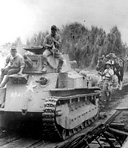 JAPANESE ADVANCING during the drive on Manila. The medium tank is a
Type 94 (1934), with a 57-mm. gun with a free traverse of 20 degrees right and
left. It had a speed of 18 to 20 miles an hour, was manned by a crew of 4,
weighed 15 tons, and was powered by a diesel engine.