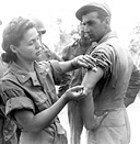 AN ARMY NURSE giving an enlisted man an inoculation. Troops arriving in
Australia were prepared for transshipment to the enemy-held islands during the
latter part of 1942. Since the number of troops in the Southwest Pacific was limited 
during the early stages, future operations were based on the movement of air
force units from island to island to gain air superiority, provide cover for the
advancing ground forces, and isolate enemy positions. As the ground forces
moved to a new position, airfields were to be established for the next jump.
Some of the first enemy positions to be taken were near Port Moresby and in the Solomons.