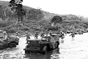 TROOPS WEARING GAS MASKS cross a stream under a protective cover of
smoke during maneuvers (top); infantrymen and jeeps
(<font size=-1><sup>1</sup>/>4</sup>-ton 4x4 truck) crossing 
a stream during training on New Caledonia, summer 1942.