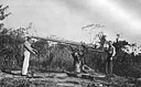 Members of a PT crew inspect a Japanese 5-inch gun after the fall of Lae