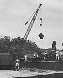 A crane barge lowers a new Packard engine into PT 242 at a Pacific base