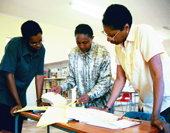 WLP volunteers Del Hornbuckle and Margaret Tryalor discuss the Dewey Decimal system with Bussi Ndawo of the Department of Education.
