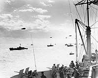 Photo # 80-G-231247:  LCI(L) convoy passes USS Ancon en route to the Normandy invasion beaches, 6 July 1943.