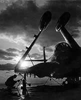 Photo # NH 97272: Airman ties down a F2H jet fighter on board USS Essex, at sunset, 1952