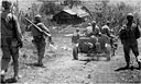 Jeep, pulling a 37-mm. antitank M3A1, passes a group of men who are advancing