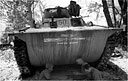 A landing vehicle, tracked, provides a shady spot for a game of cards during a lull in the fighting