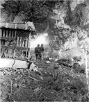 MARINE USING A FLAME THROWER TO ROUT THE ENEMY from a cave turns his face from the intense heat