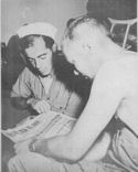 U.S. COAST GUARDSMAN MORTIMER R. SPITALNY OF ELIZABETH, N.J., AND PARATROOPER K. BRONES OF INDEPENDENCE, IOWA, LOOK OVER A SICILIAN NEWSPAPER ABOARD A COAST GUARD-MANNED TRANSPORT PARTICIPATING IN THE INVASION