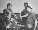 A RELAXING U.S. PARATROOPER, TELLS TWO U.S. COAST GUARDSMEN WHAT HAPPENED WHEN HIS UNIT DROPPED ON SICILIAN SOIL, ABOARD A COAST GUARD-MANNED TRANSPORT