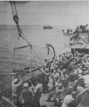 WHILE WOUNDED ARE BROUGHT BACK TO A COAST GUARD-FANNED TRANSPORT, OTHER SOLDIERS ABOARD THE SHIP ARE READY TO TAKE THEIR TURN TO JOIN THE INVADERS OF SICILY