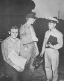 COAST GUARDSMAN EARL SAUTER TALKS TO A WISTFUL PAIR OF YOUNG GERMAN PRISONERS ABOARD A COAST GUARD MANNED TRANSPORT ENROUTE TO A NORTH AFRICAN PORT