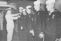 CAPTAIN RAYMOND J. KAUEBKAN, U.S. COAST GUARD, PRESENTS THE PURPLE HEART TO FIVE MEN WOUNDED DURING THE SALERNO ACTION