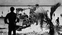 Figure 7.--LST being unloaded at reef line. Here the depth of water between reef and shore is such that vehicles can easily move from shipi to beach. (Marines in the Marianas.)